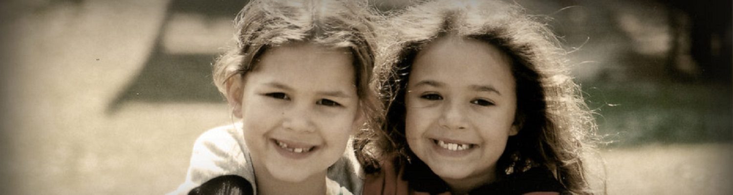 Two Lumbee girls around 10 years of age smile at the camera. One has her arm around the other.