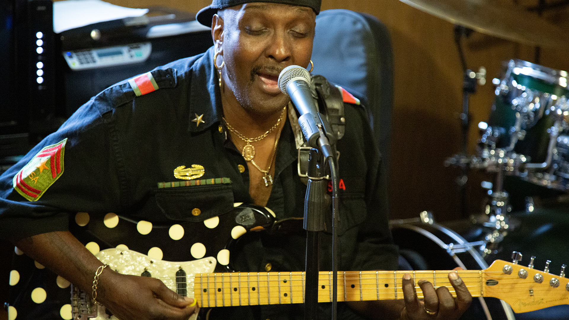 Man holds an electric bass and sings into microphone